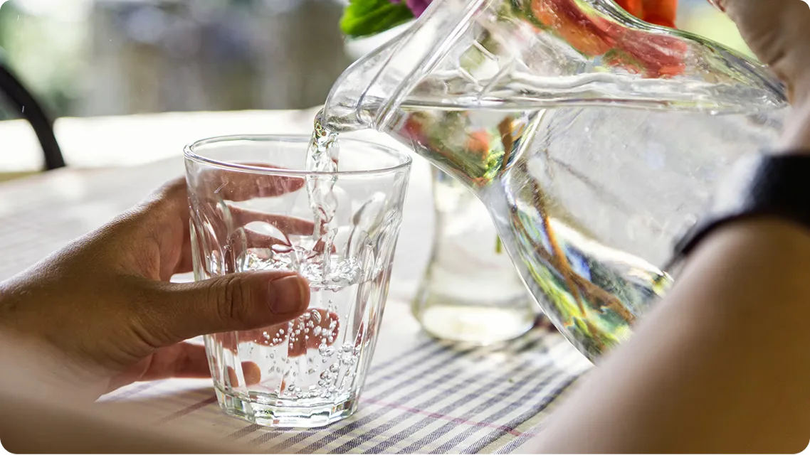 Wasser wird aus einem Krug in ein Glas gegossen